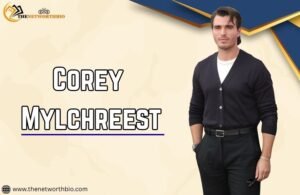 Corey Mylchreest standing in black dress with abstract background