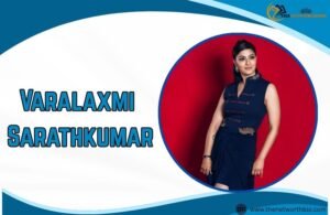 Varalaxmi Sarathkumar standing in blue dress against abstract background